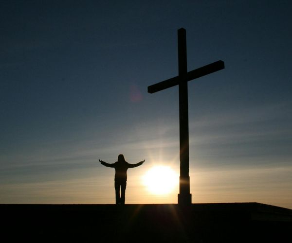 Silhouette of a person meditating against a vanilla-colored sunrise, symbolizing inner peace.